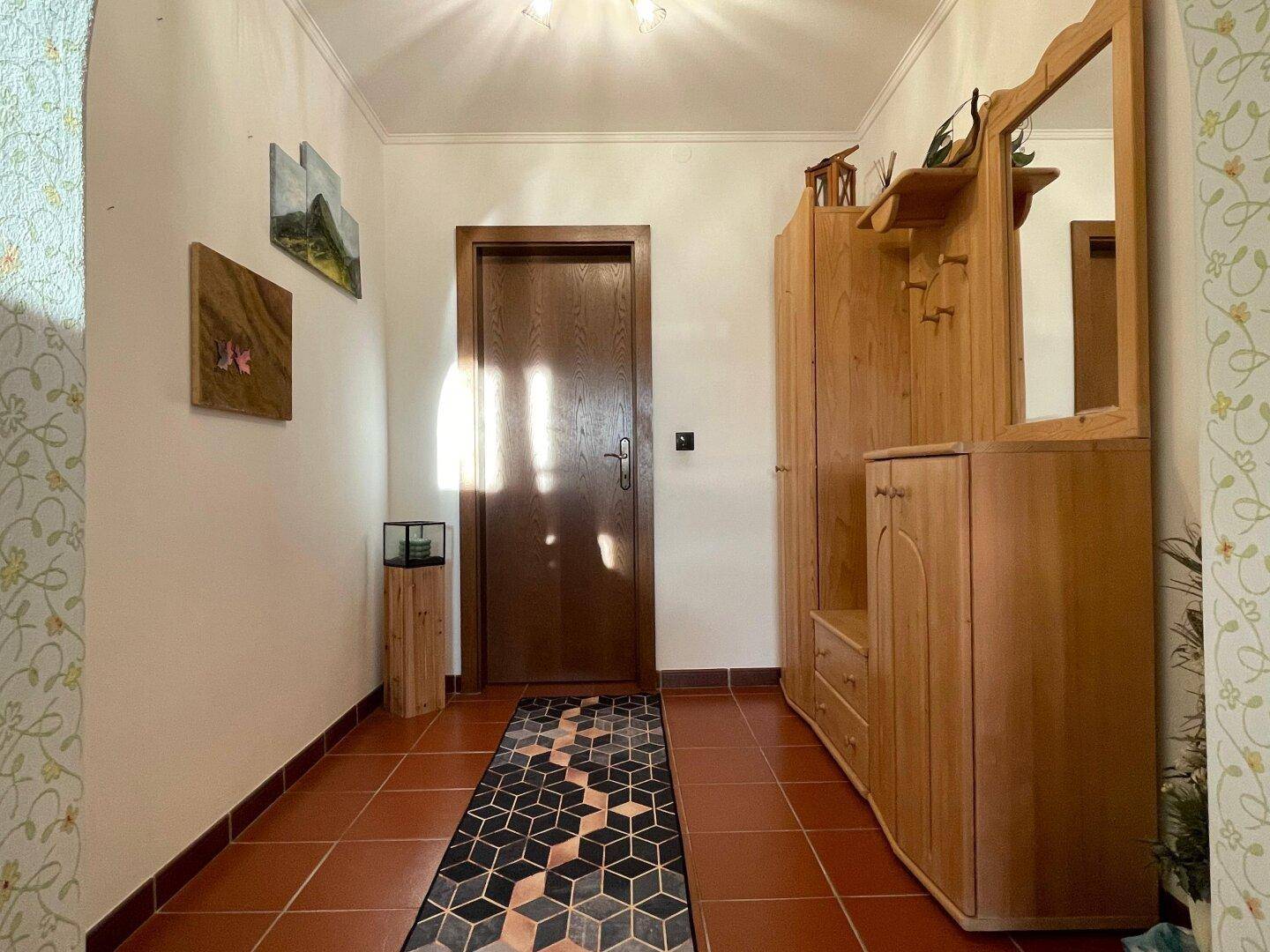 Heller Eingangsbereich mit Terrakotta-Fliesenboden und traditionellen Holzmöbeln.