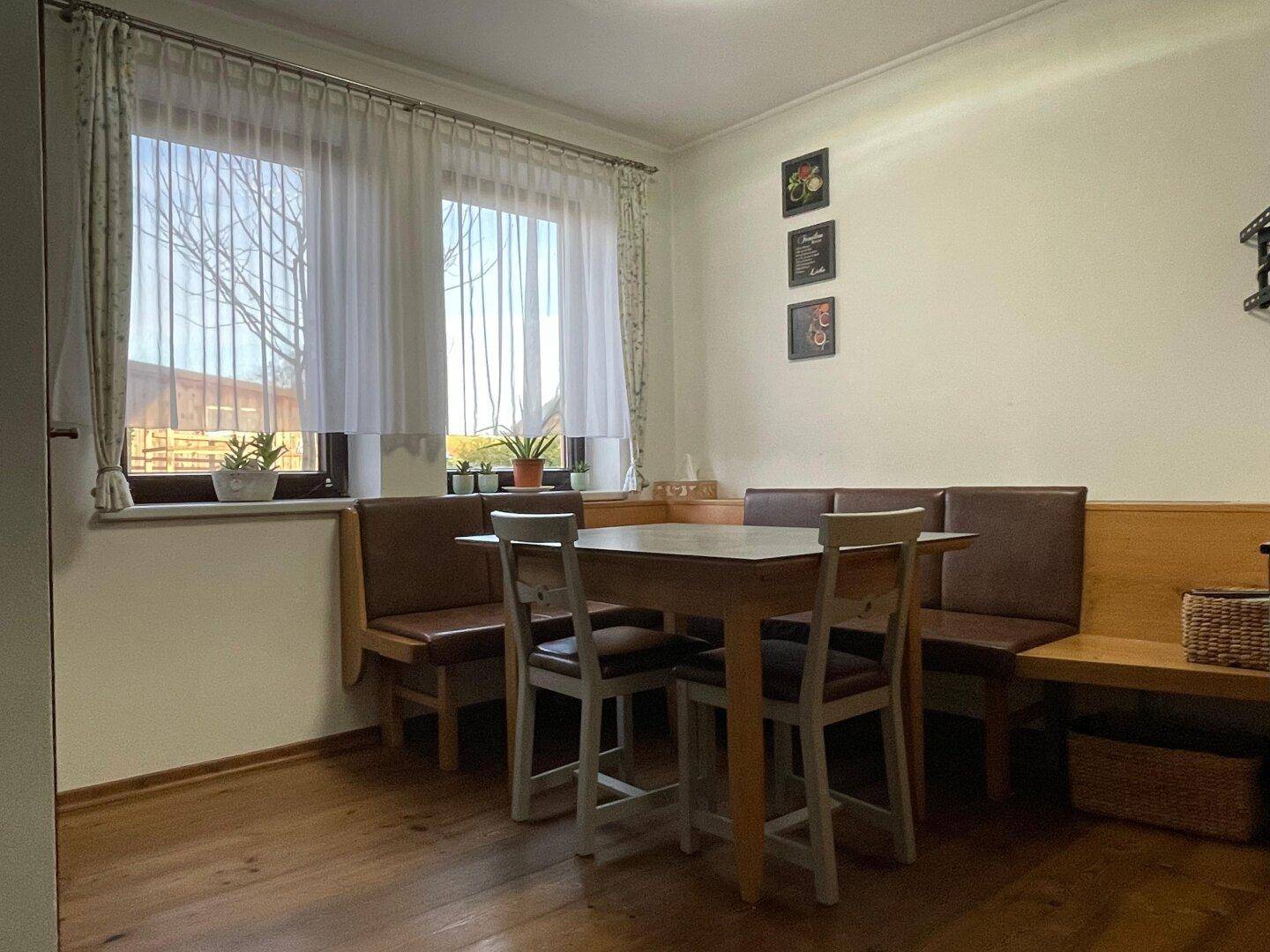 Gemütlicher Essbereich mit Holztisch, Eckbank und großen Fenstern für viel Tageslicht.