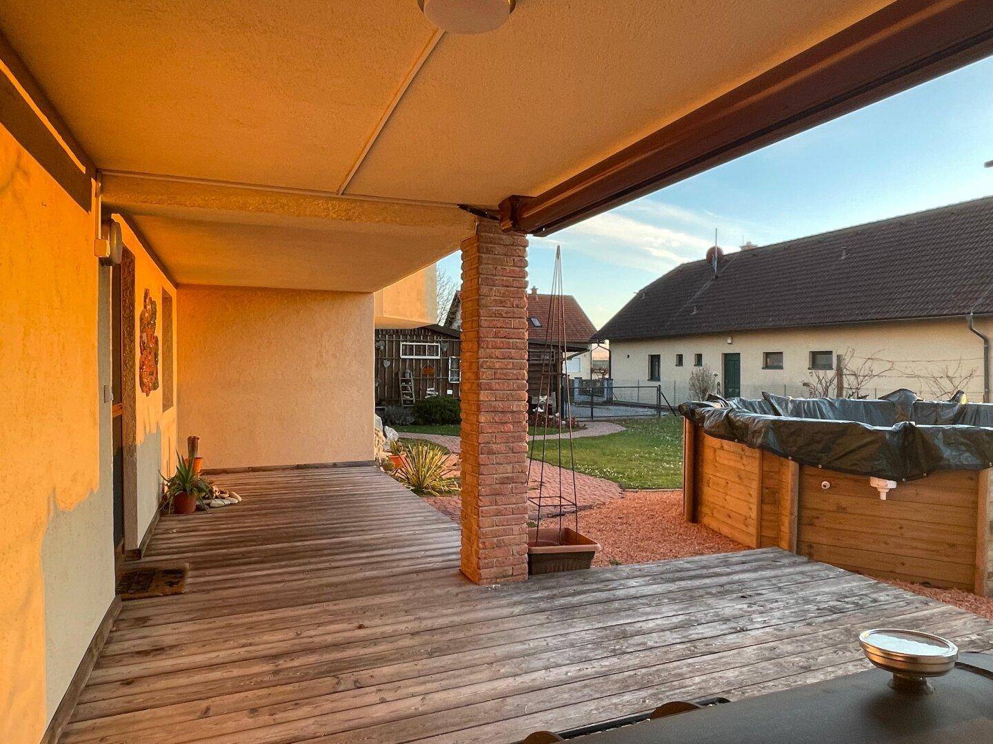 Überdachte Holzterrasse mit Blick auf den Garten und die ländliche Umgebung.