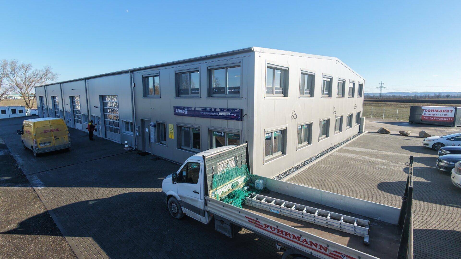 Vorderansicht des Gewerbegebäudes mit Bürofenstern und einem Lieferwagen auf dem Parkplatz.