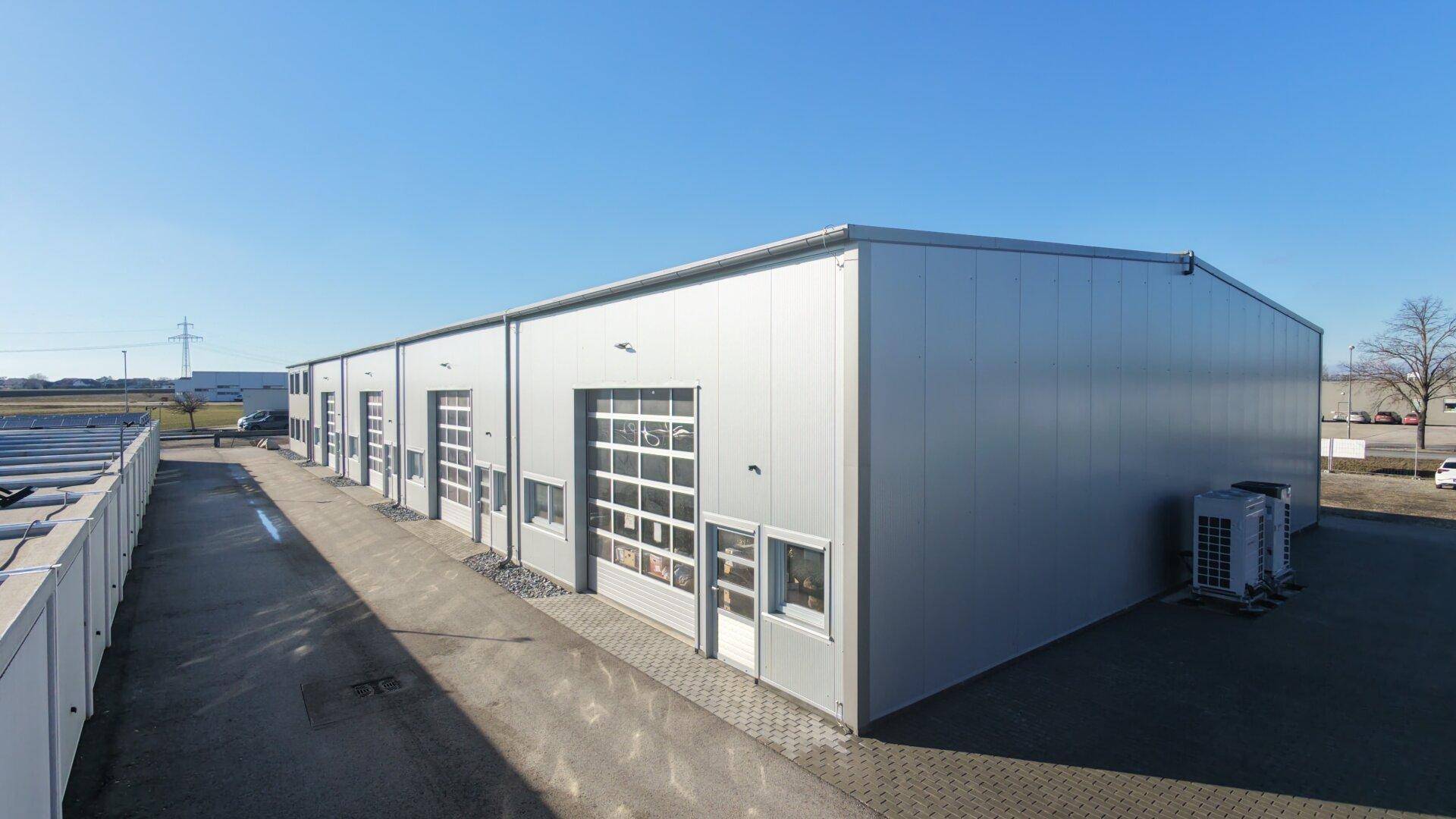 Seitenansicht des modernen Gewerbegebäudes mit mehreren Garagentoren und externen Klimaanlagen.
