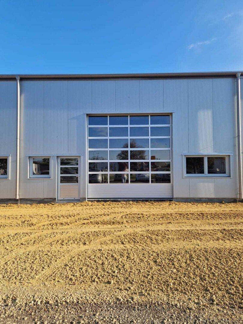 Detailansicht eines großen, verglasten Garagentors an der Fassade des modernen Gewerbegebäudes.