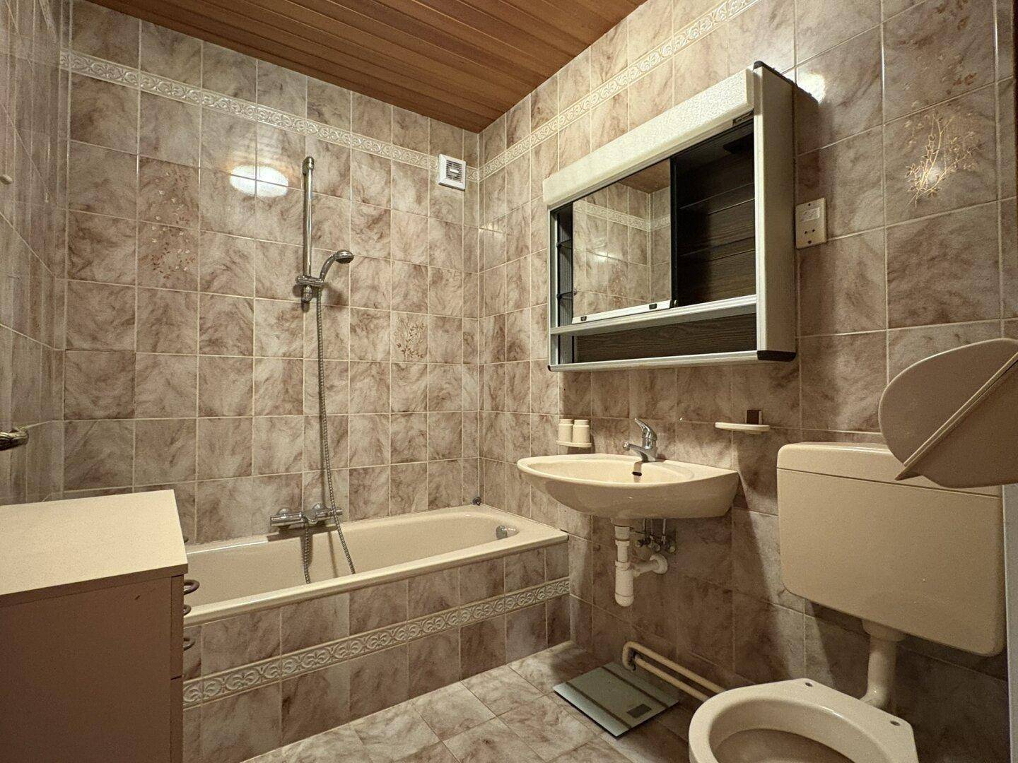 Gefliestes Badezimmer mit Badewanne, Waschbecken und Toilette in traditionellem Stil.