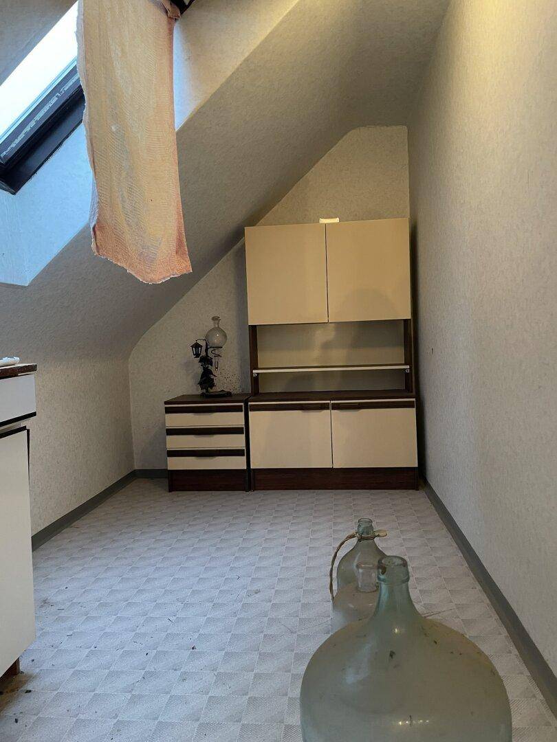 Dachbodenraum mit Schrägen, Dachfenster und einfachen Möbeln zur Lagerung.