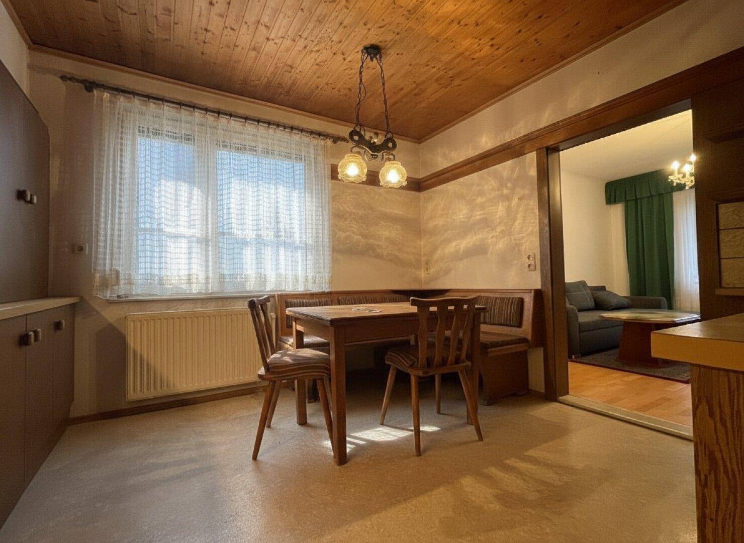 Traditioneller Essbereich mit Holztäfelung, Teppichboden und Zugang zum Wohnzimmer.