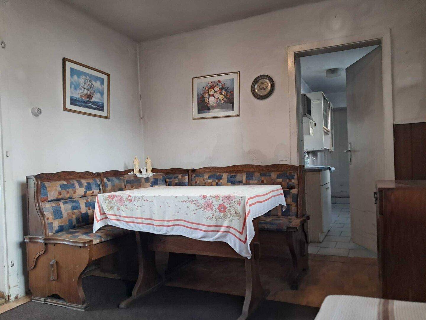 Gemütlicher Essbereich mit traditioneller Eckbank, Holztisch und Bildern an der Wand.
