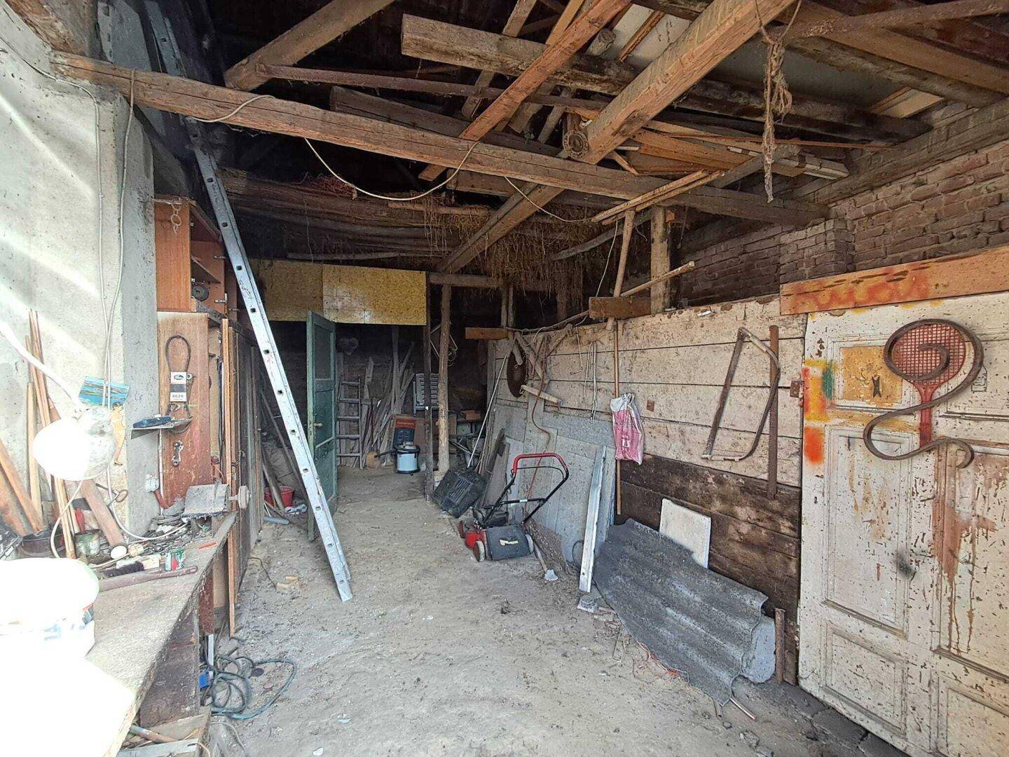 Rustikaler Werkstattraum mit Holzbalken, Leiter und verschiedenen Geräten, ideal für Heimwerker.