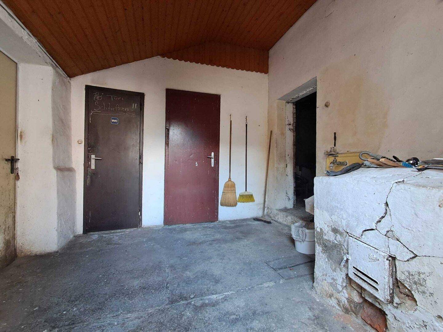 Einfacher Hauswirtschaftsraum mit Holzdachschräge und zwei Türen, ideal als Abstellraum.