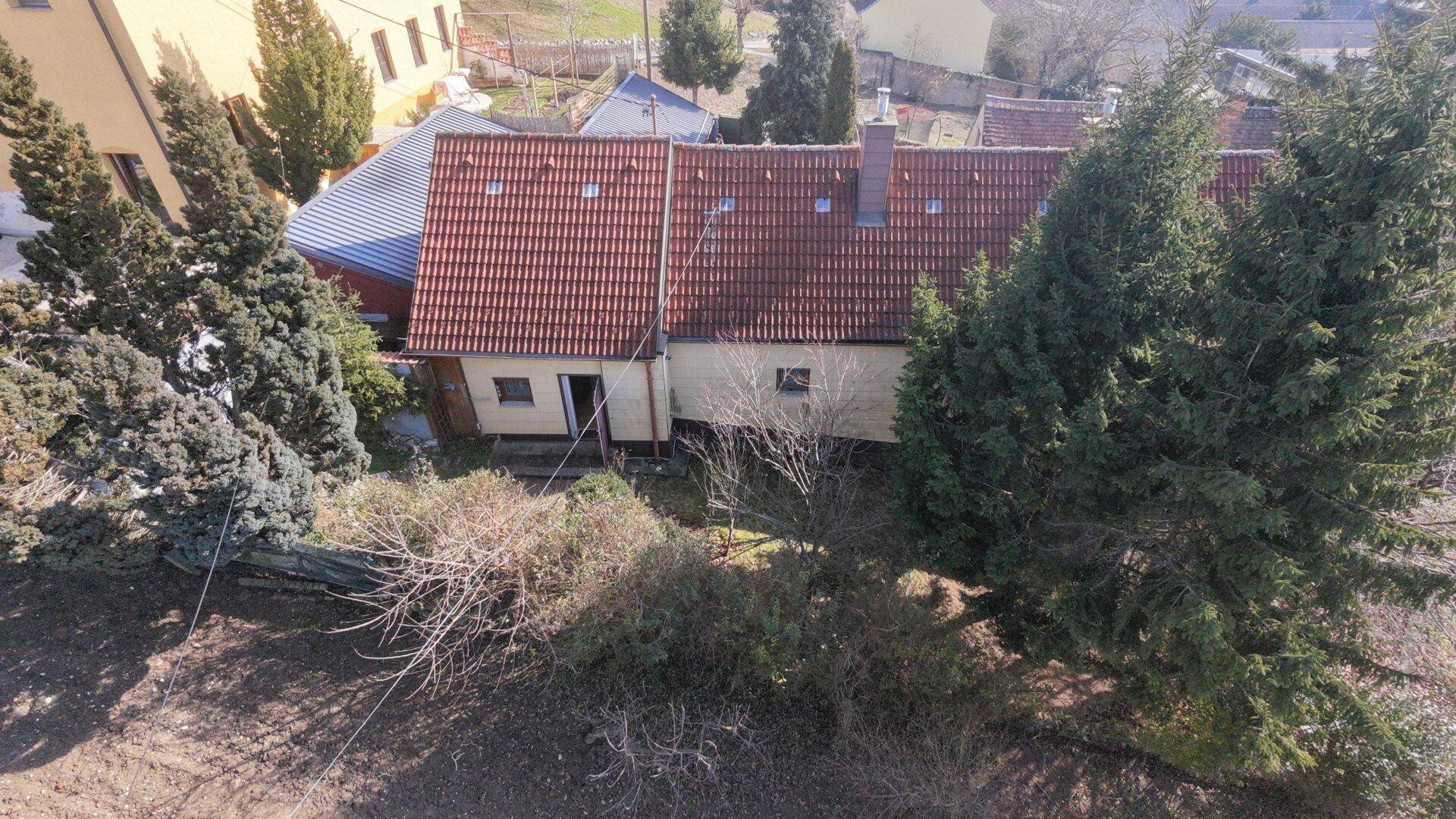 Luftaufnahme des Anwesens mit rotem Ziegeldach, umgeben von Bäumen und einem Gartenbereich.