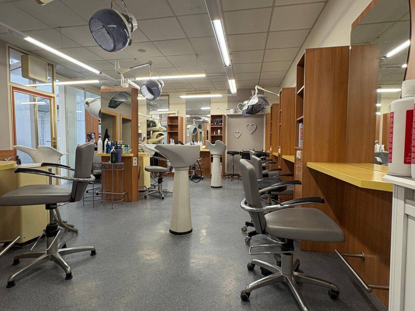Friseursalon mit mehreren Arbeitsplätzen, Waschbecken und Trockenhauben, ausgestattet für den Betrieb.