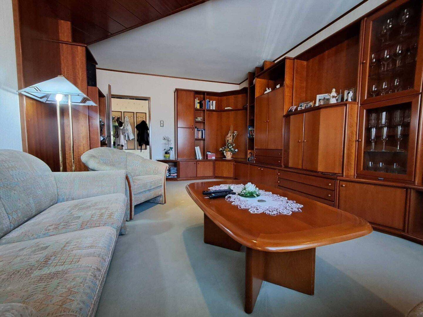 Wohnzimmer mit umfangreichen Holzschränken, Teppichboden und gemütlicher Einrichtung, ideal zum Entspannen.