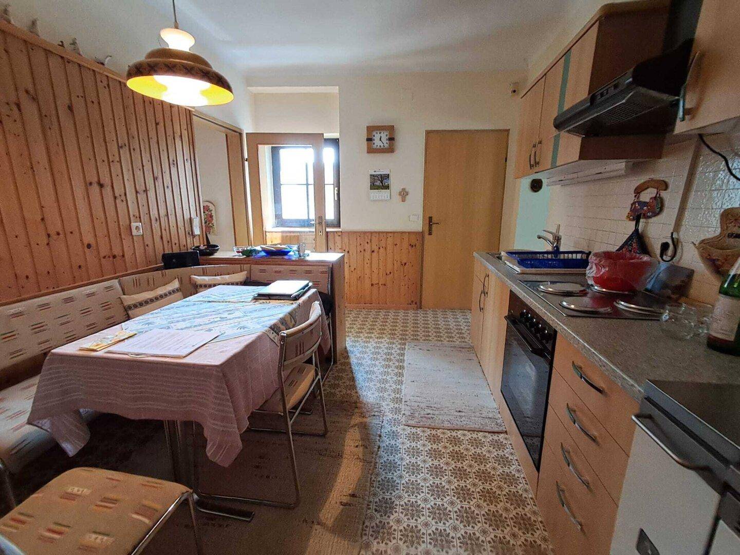 Helle Küche mit Fenster, Holzelementen und einer gemütlichen Essecke für die Familie.