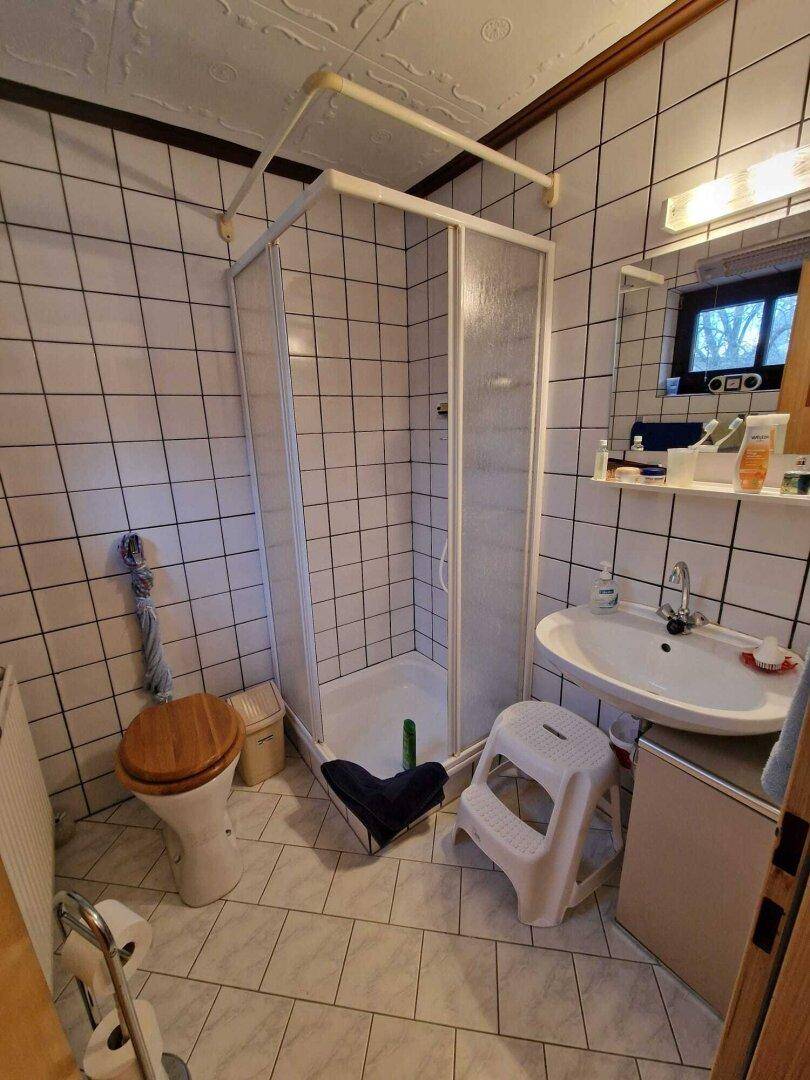 Funktionales Badezimmer mit Duschkabine, Toilette und Einzelwaschbecken, komplett gefliest.