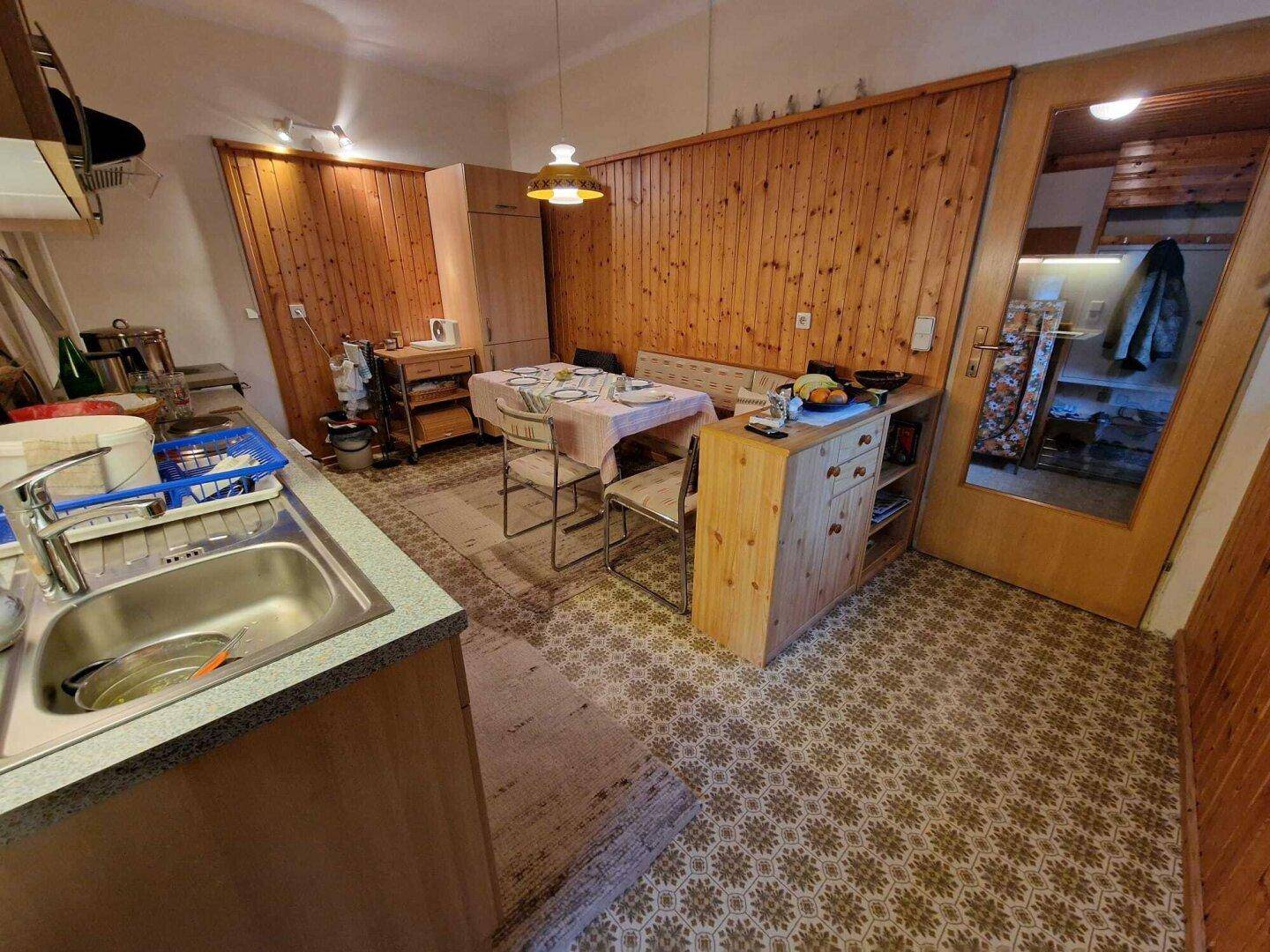 Funktionale Wohnküche mit Esstisch, Holzvertäfelung und praktischer Küchenzeile.