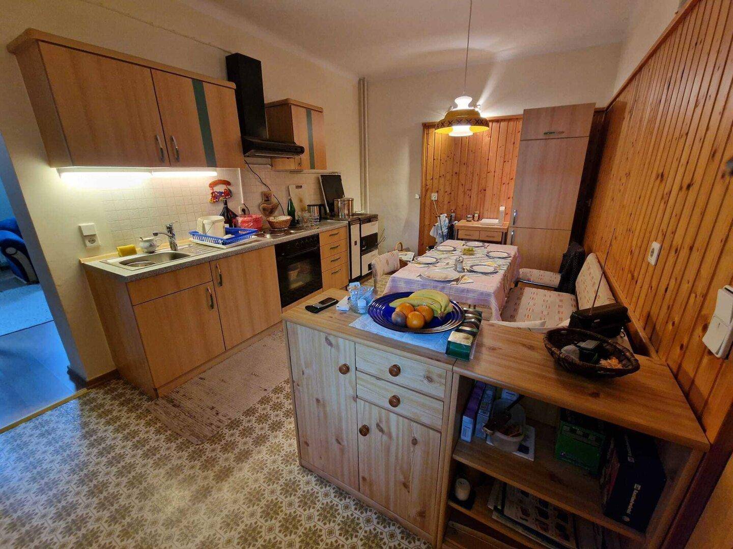 Kleine, gemütliche Wohnküche mit Holzschränken, Essbereich und traditioneller Einrichtung.