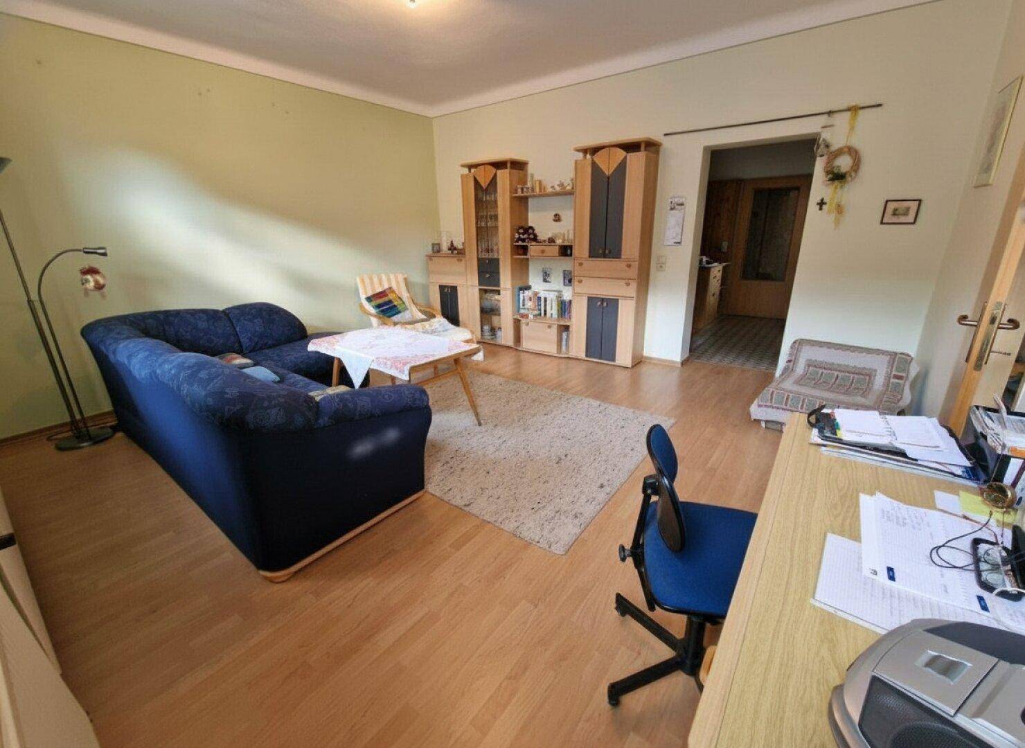 Komfortables Wohnzimmer mit Sofa, Schränken und Laminatboden, ideal zum Entspannen.