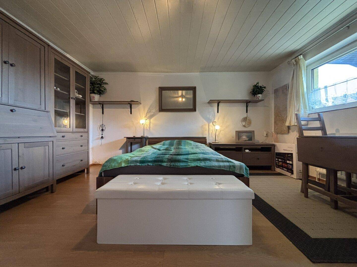 Einladendes Schlafzimmer mit Holzboden, bequemen Möbeln und viel Stauraum.