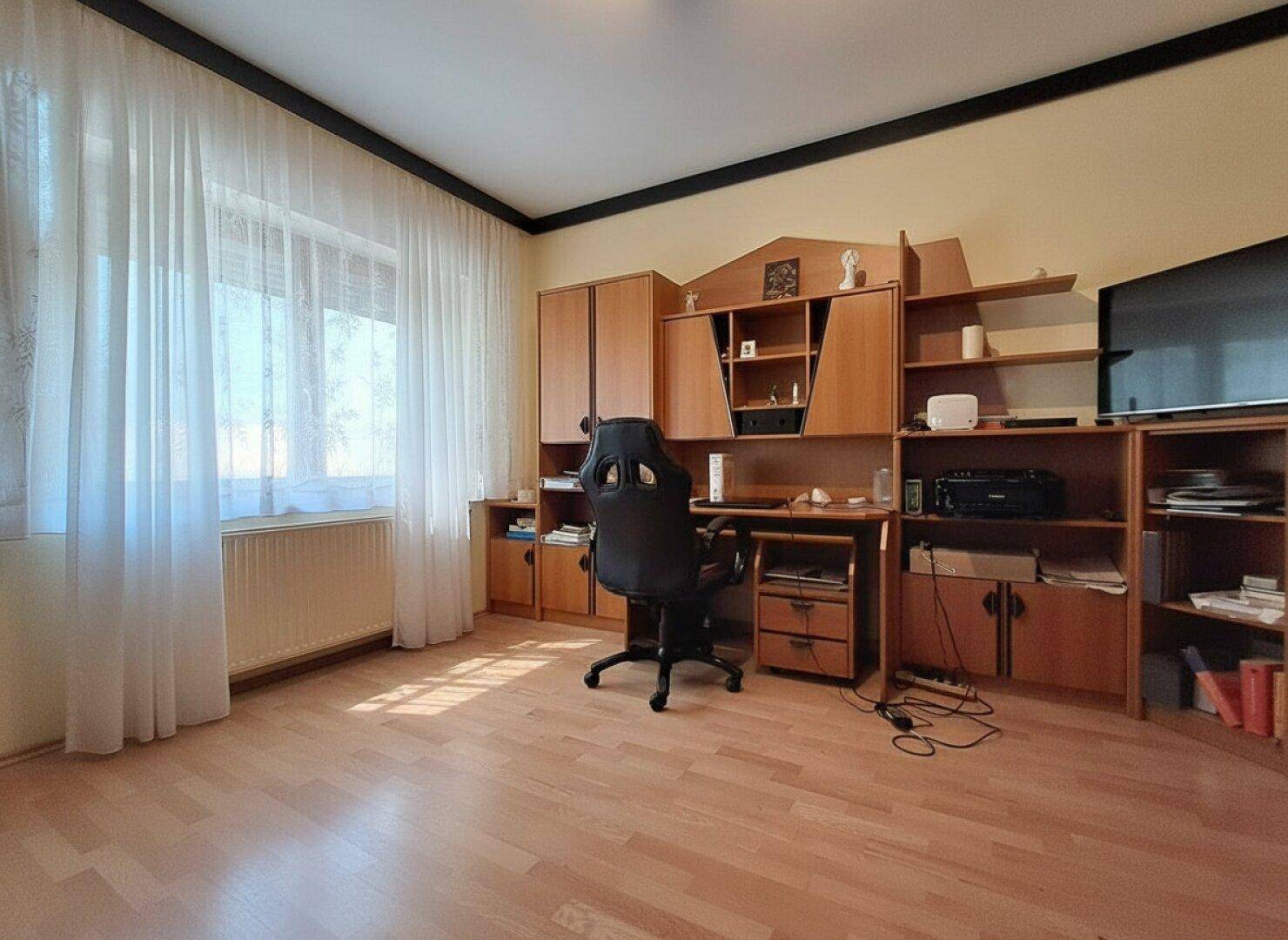 Geräumiges Arbeitszimmer mit großem Schreibtisch, Regalen und Holzfußboden.
