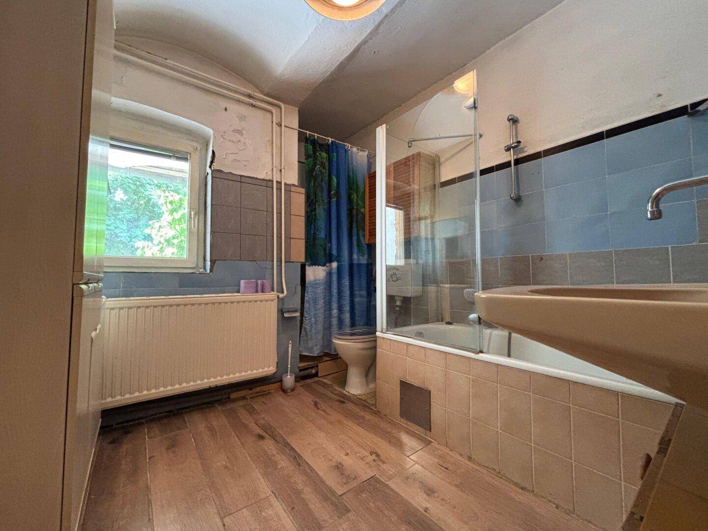 Ein Badezimmer mit Badewanne, Duschabtrennung, Waschbecken und Fenster.