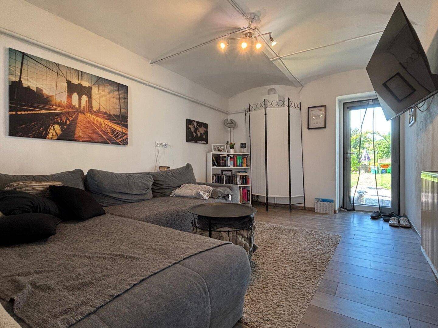 Geräumiges Wohnzimmer mit großem Sofa, Teppich und Zugang zum Gartenbereich.