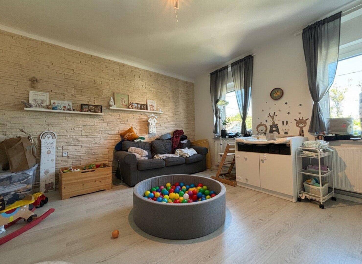 Heller Kinderzimmer oder Spielbereich mit Steinwand, Sofa und Spielzeug.
