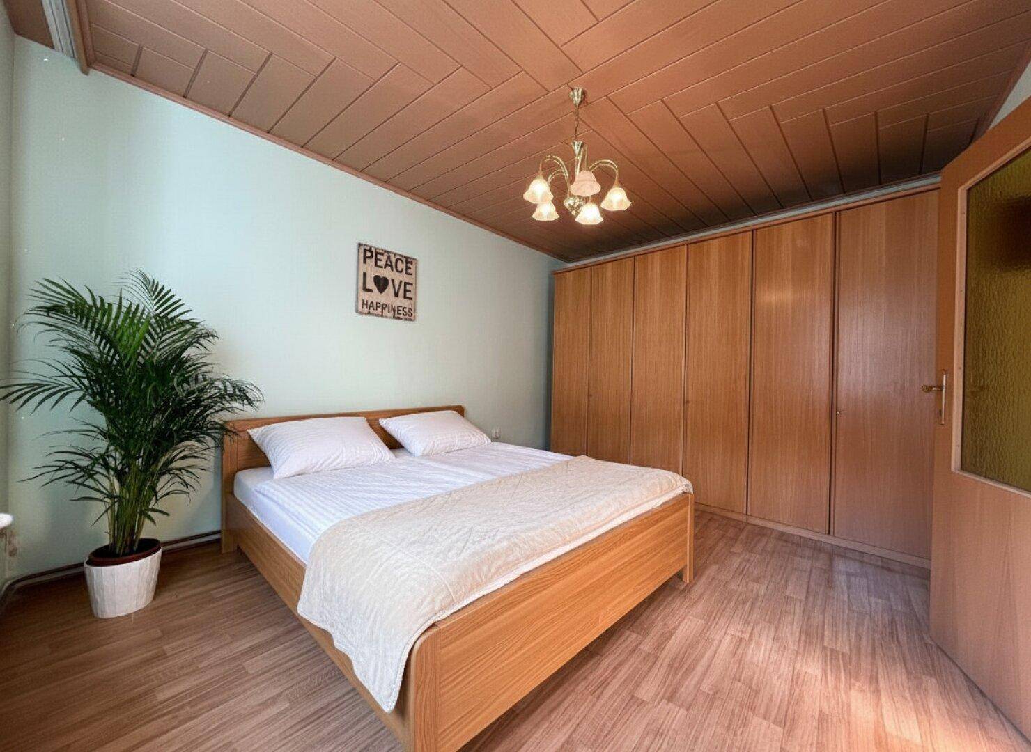 Gemütliches Schlafzimmer mit Doppelbett, großem Holzschrank und Holzpaneeldecke.