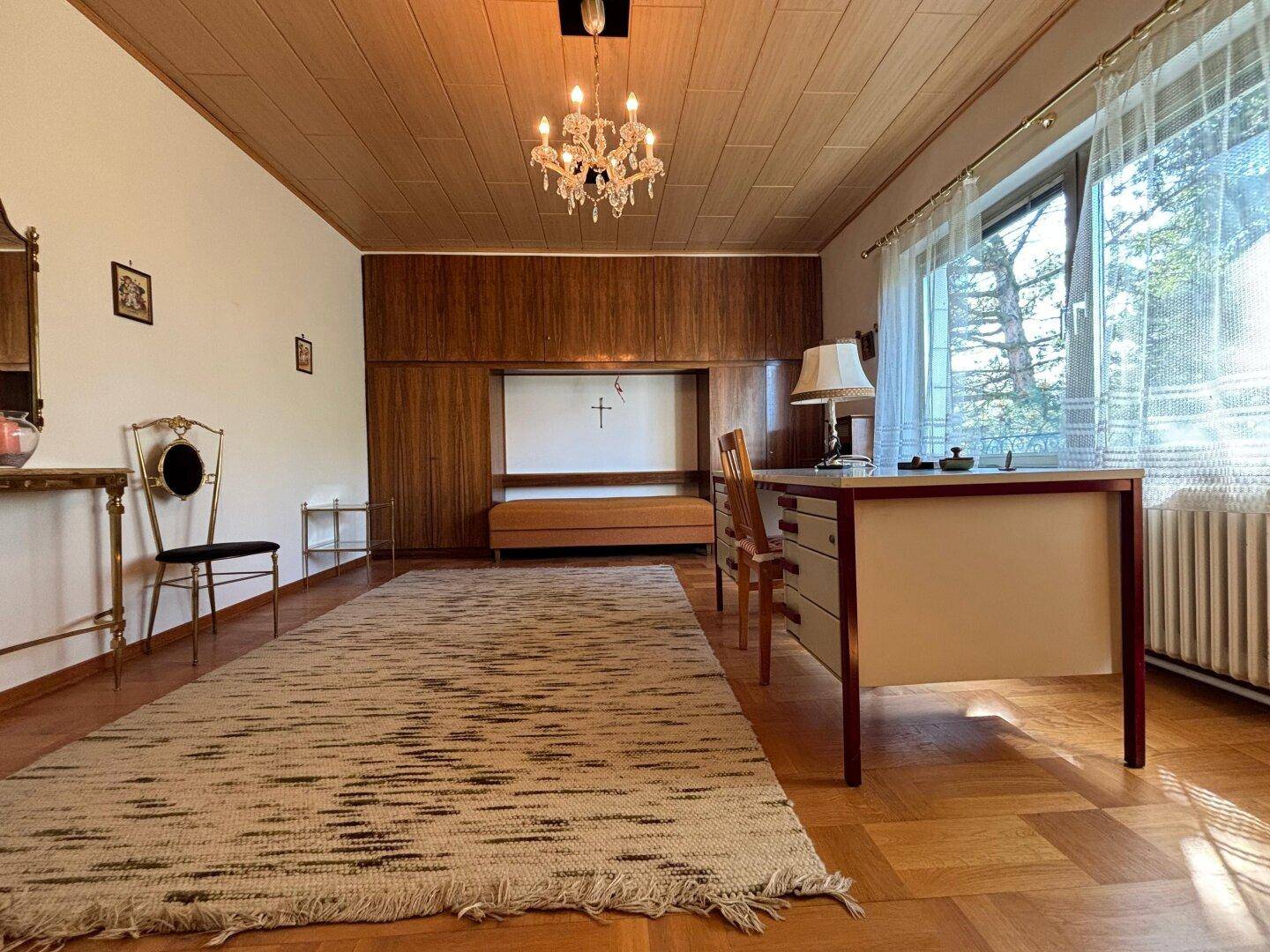 Geräumiges Arbeitszimmer mit Parkettboden, Holzvertäfelung und großem Fenster.