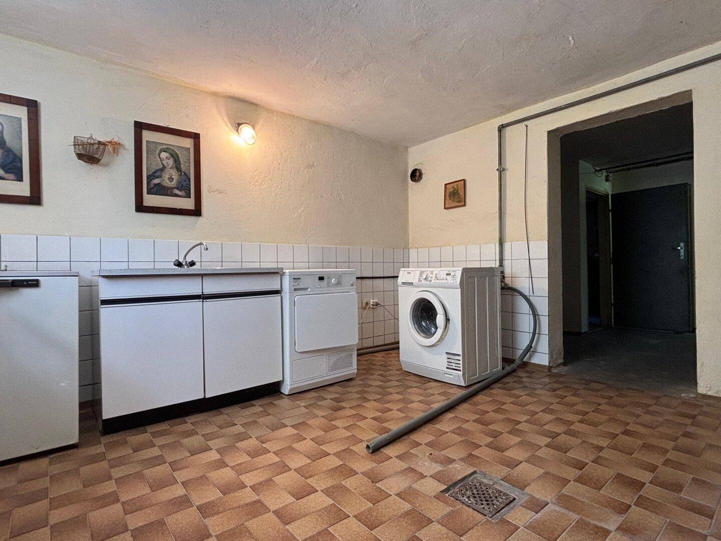 Praktische Waschküche im Keller mit Waschmaschine, Trockner und Spülbecken.