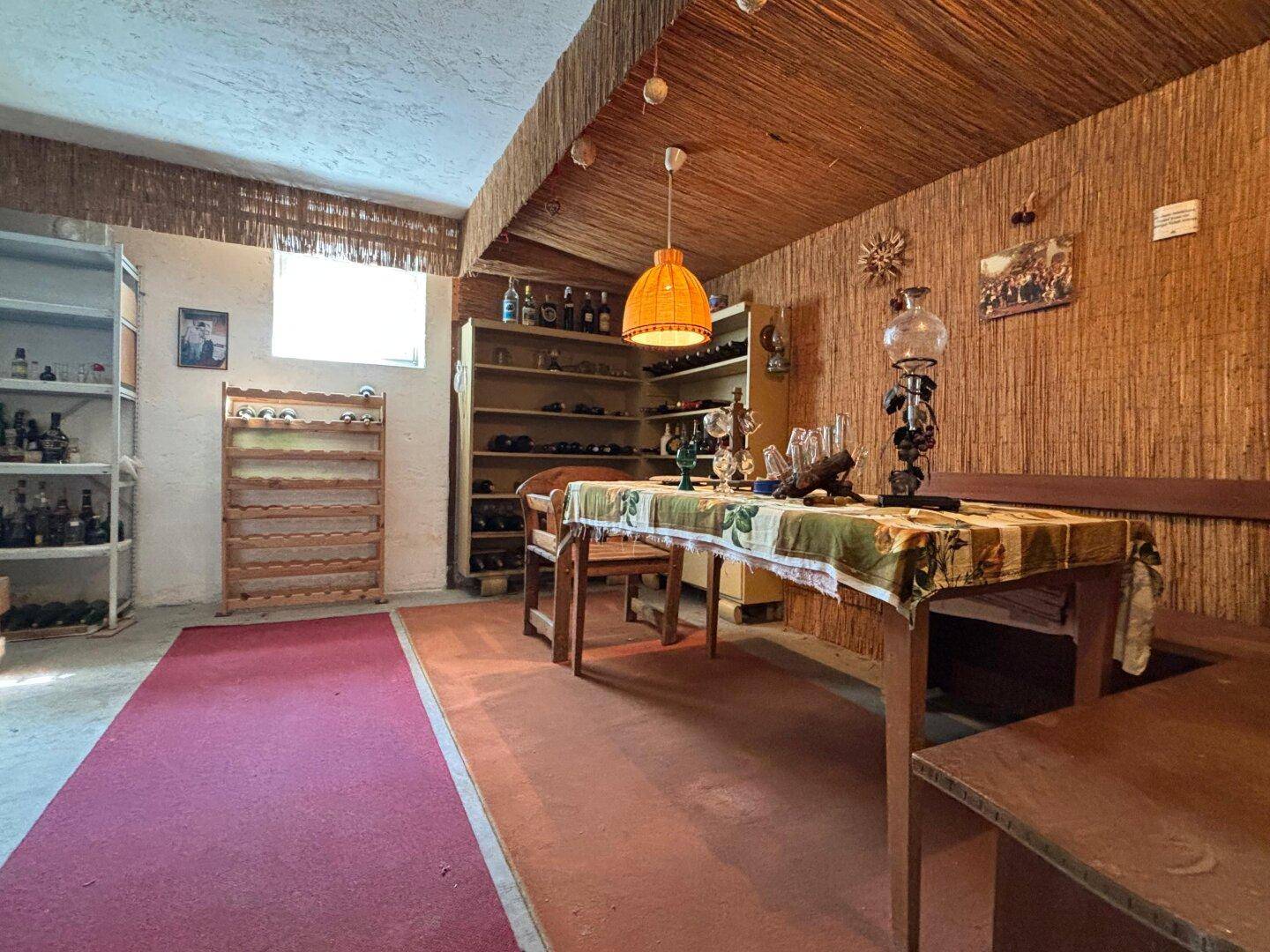 Rustikaler Kellerraum mit Weinregalen, Esstisch und gemütlicher Atmosphäre.