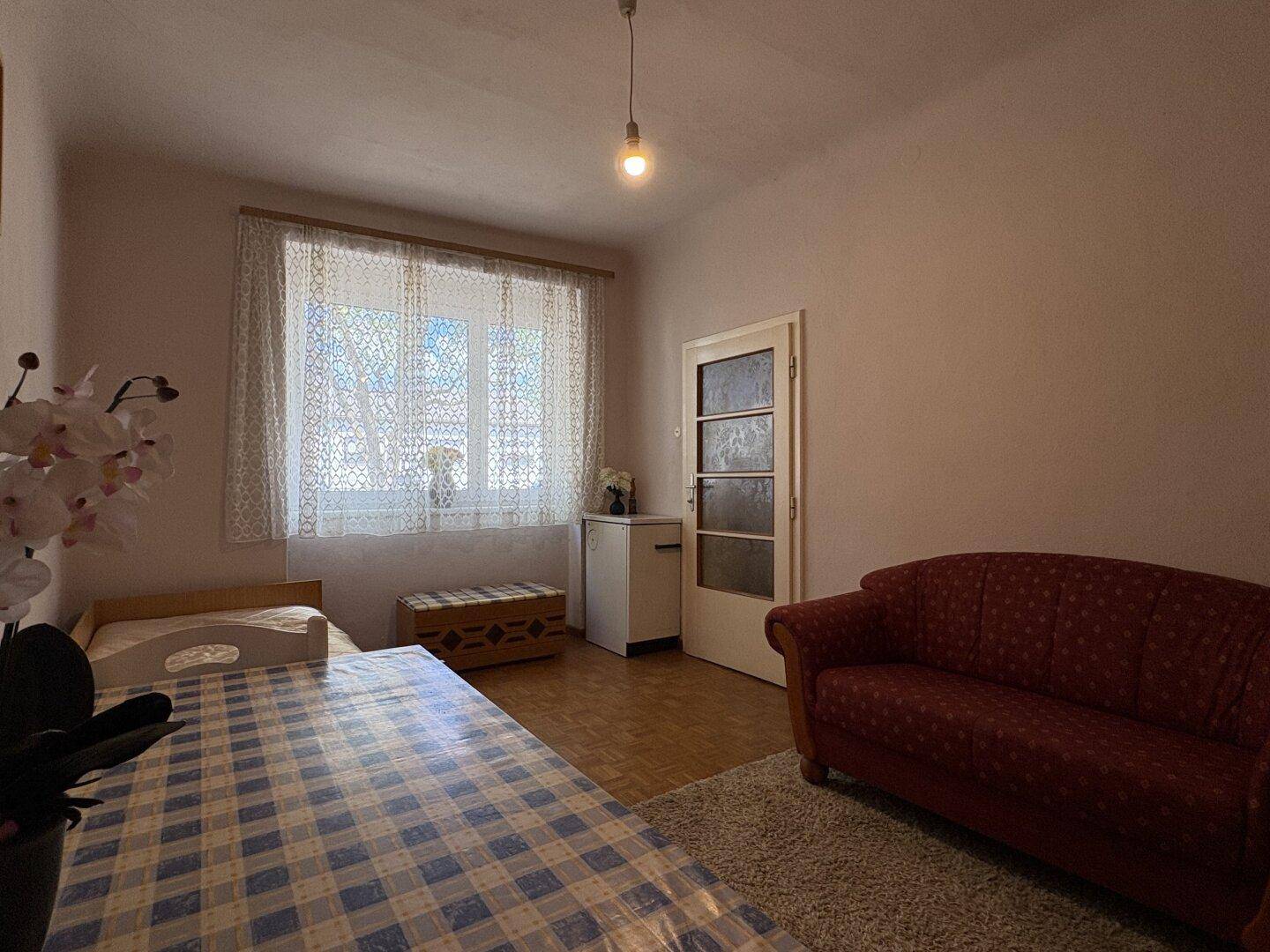 Helles Schlafzimmer mit Einzelbett, Fenster und einfacher Einrichtung für Gäste oder Kinder.