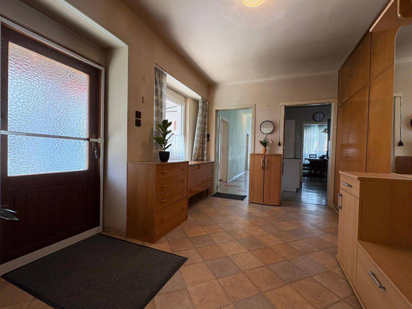 Geräumiger Eingangsbereich mit Fliesenboden, Holzmöbeln und Fenster, hell und einladend.