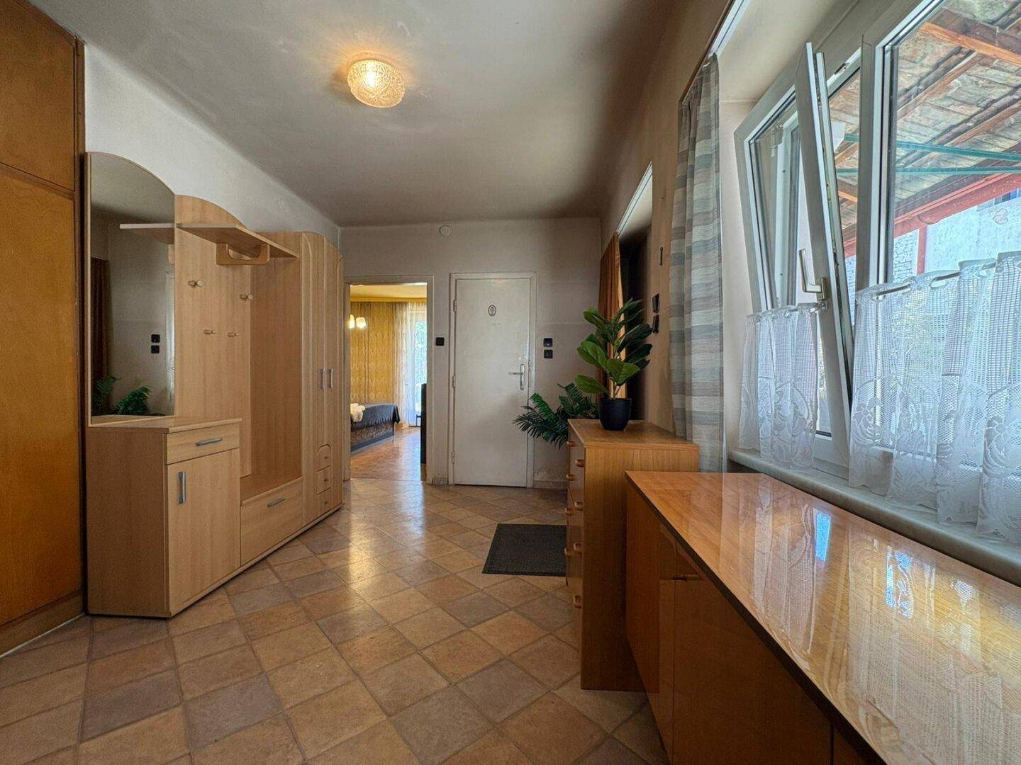 Heller Flur mit Fliesenboden, Garderobe und Fenster mit Blick nach draußen, praktisch und funktional.
