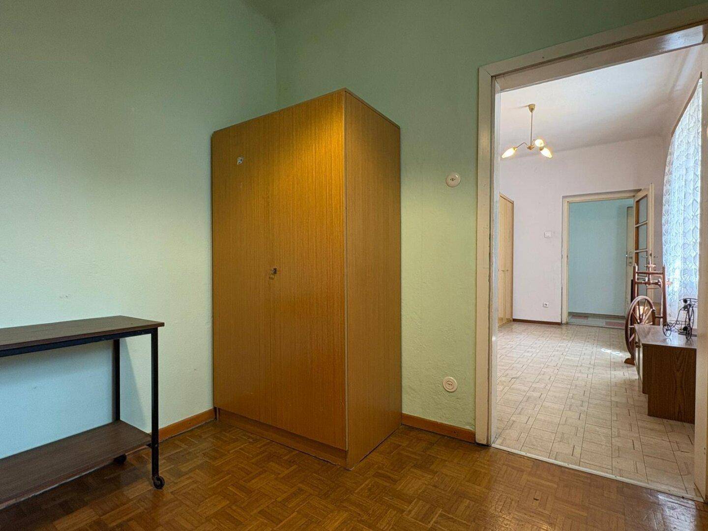 Einfaches Zimmer mit Holzschrank, grünen Wänden und Zugang zu anderen Bereichen des Hauses.