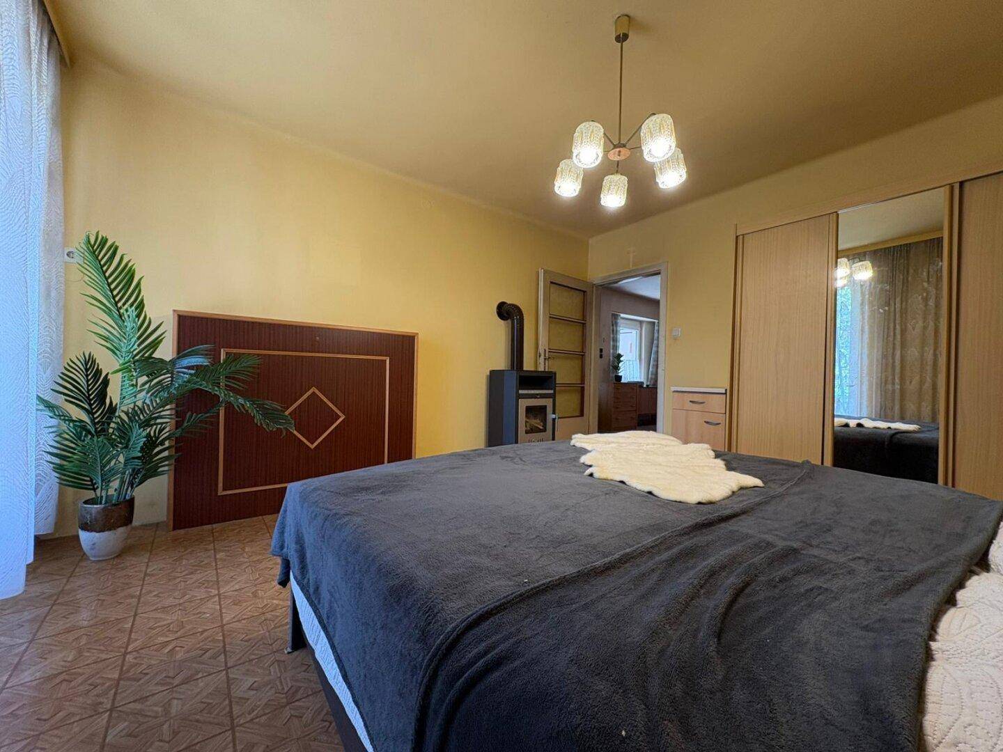 Schlafzimmer mit Doppelbett, Kaminofen und gelben Wänden, sorgt für gemütliche Wärme.