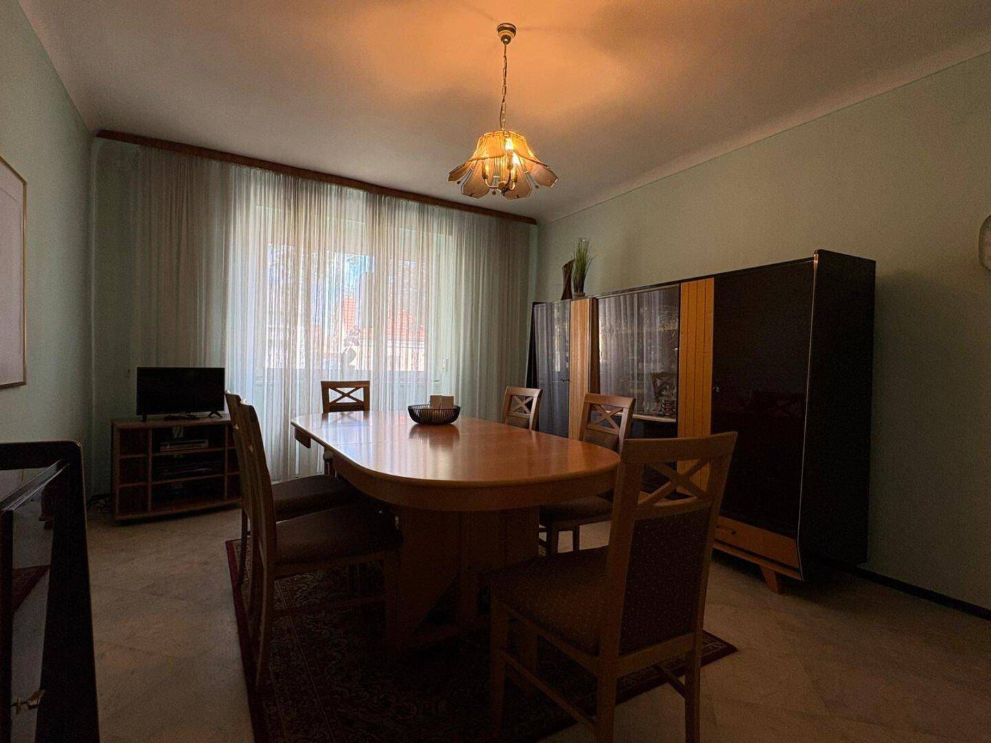 Geräumiges Esszimmer mit großem Holztisch, Stühlen und Vitrine für Familienessen.