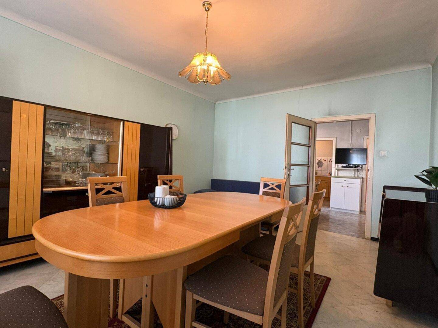 Esszimmer mit Holztisch, Stühlen und Vitrine, angrenzend an die Küche für kurze Wege.