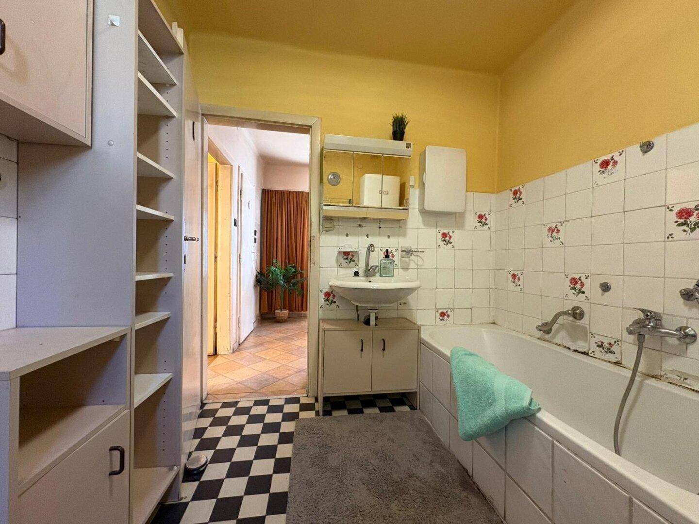 Badezimmer mit Waschbecken, Badewanne und Regalen, gefliesten Wänden und Boden.