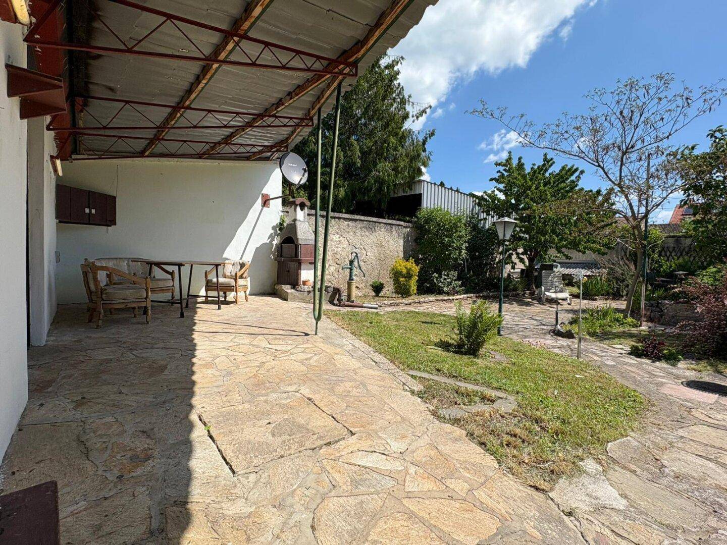 Großer Garten mit überdachter Terrasse, Grillplatz und Sitzgelegenheiten für entspannte Stunden.