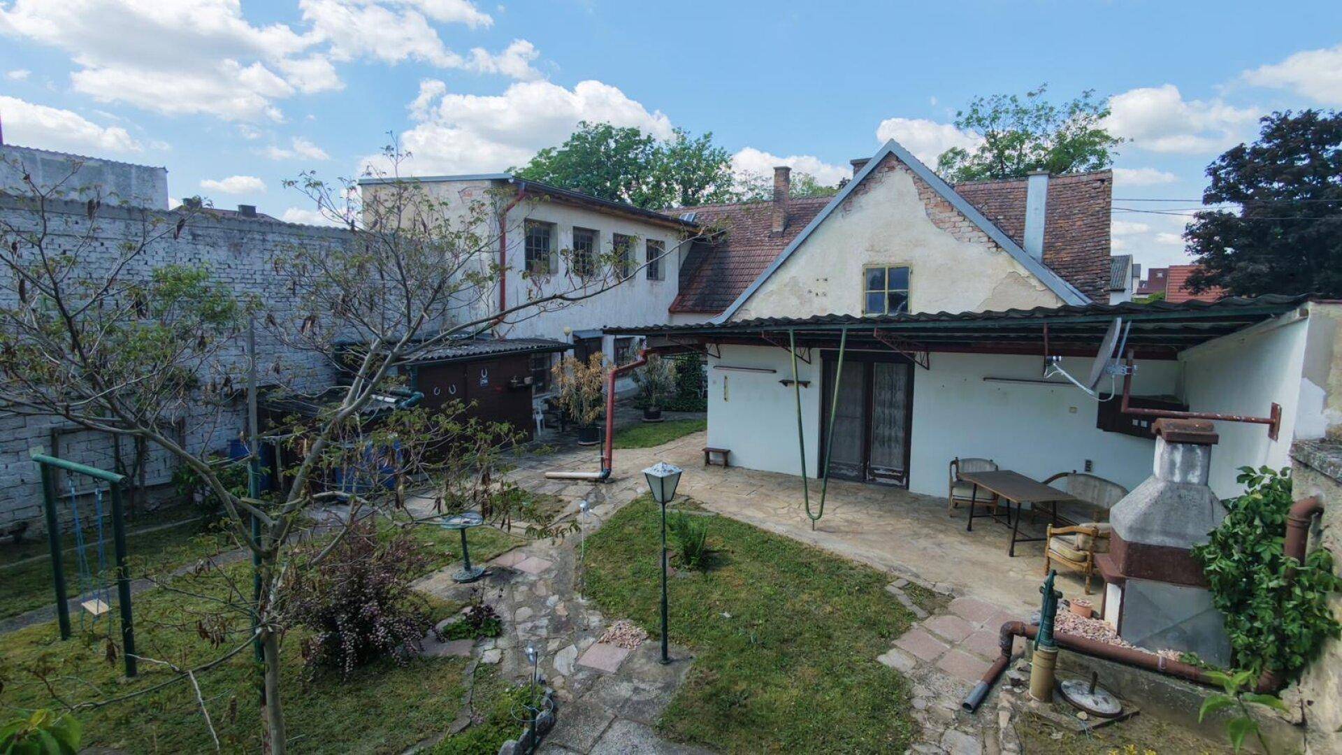 Weitläufiger Garten mit Rasenfläche, Schaukel und Blick auf das Gebäude unter blauem Himmel.