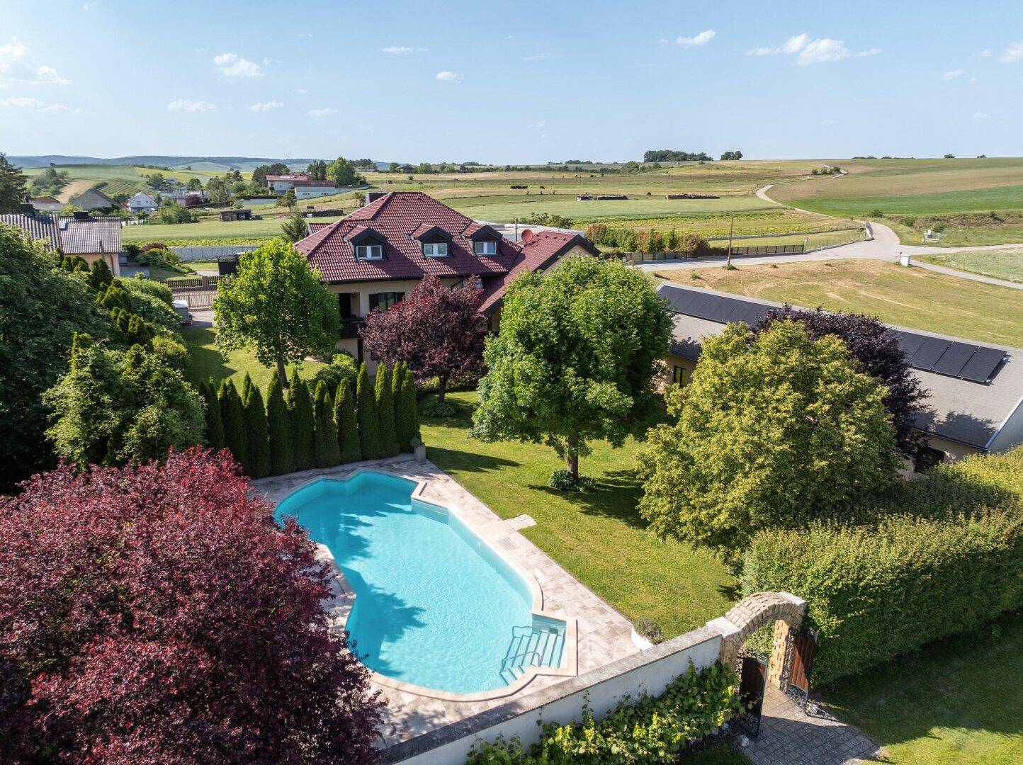 Weitläufiges Anwesen mit großem Pool, umgeben von einem gepflegten Garten und ländlicher Landschaft.