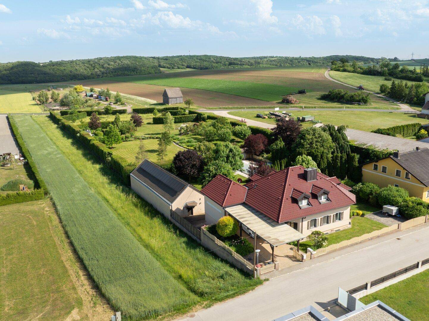 Gesamtansicht des Anwesens mit Haus, Carport und weitläufigem Garten in ländlicher Umgebung.