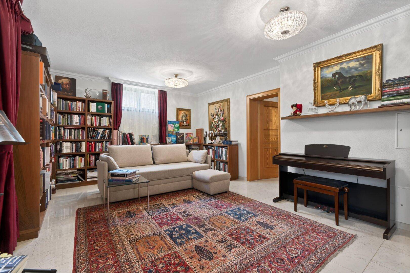 Ruhiges Lesezimmer im Keller mit Bücherregalen, Sofa und Klavier.