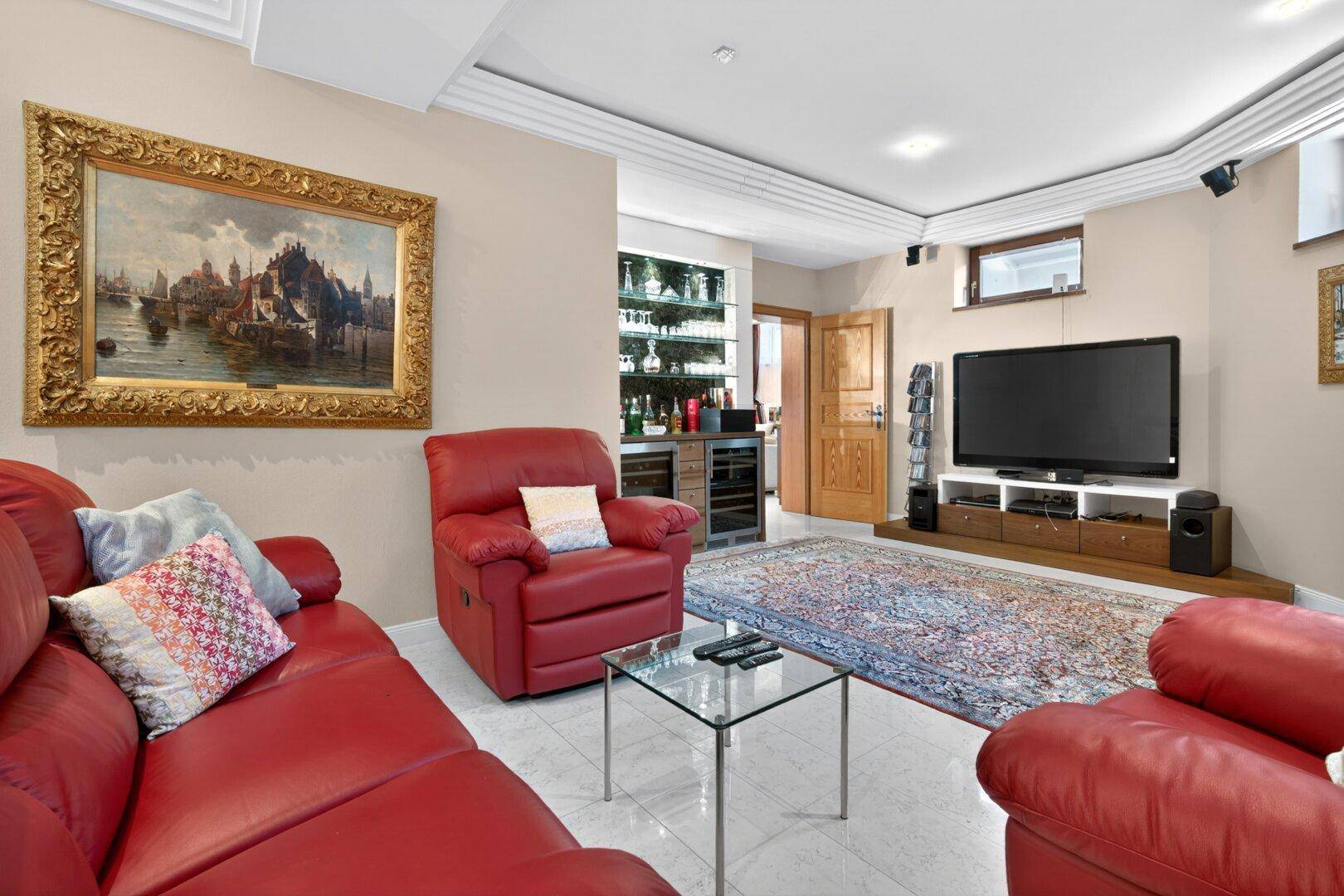 Gemütlicher Medienraum im Keller mit Ledersofas, großem Fernseher und Hausbar.