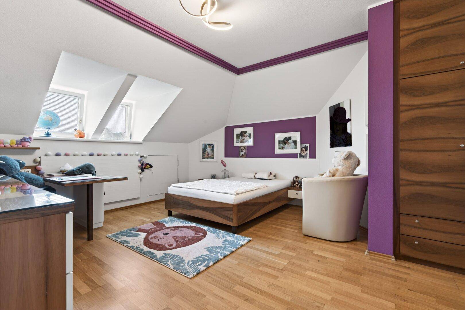 Kinderzimmer im Dachgeschoss mit Holzboden, Dachfenstern und farbenfroher Dekoration.