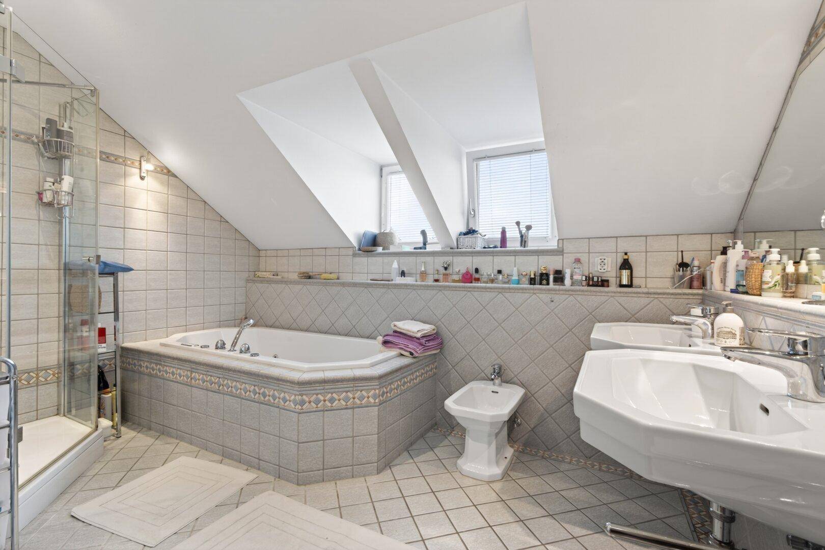 Großes Badezimmer im Dachgeschoss mit Eckbadewanne, Dusche, Bidet und Doppelwaschbecken.