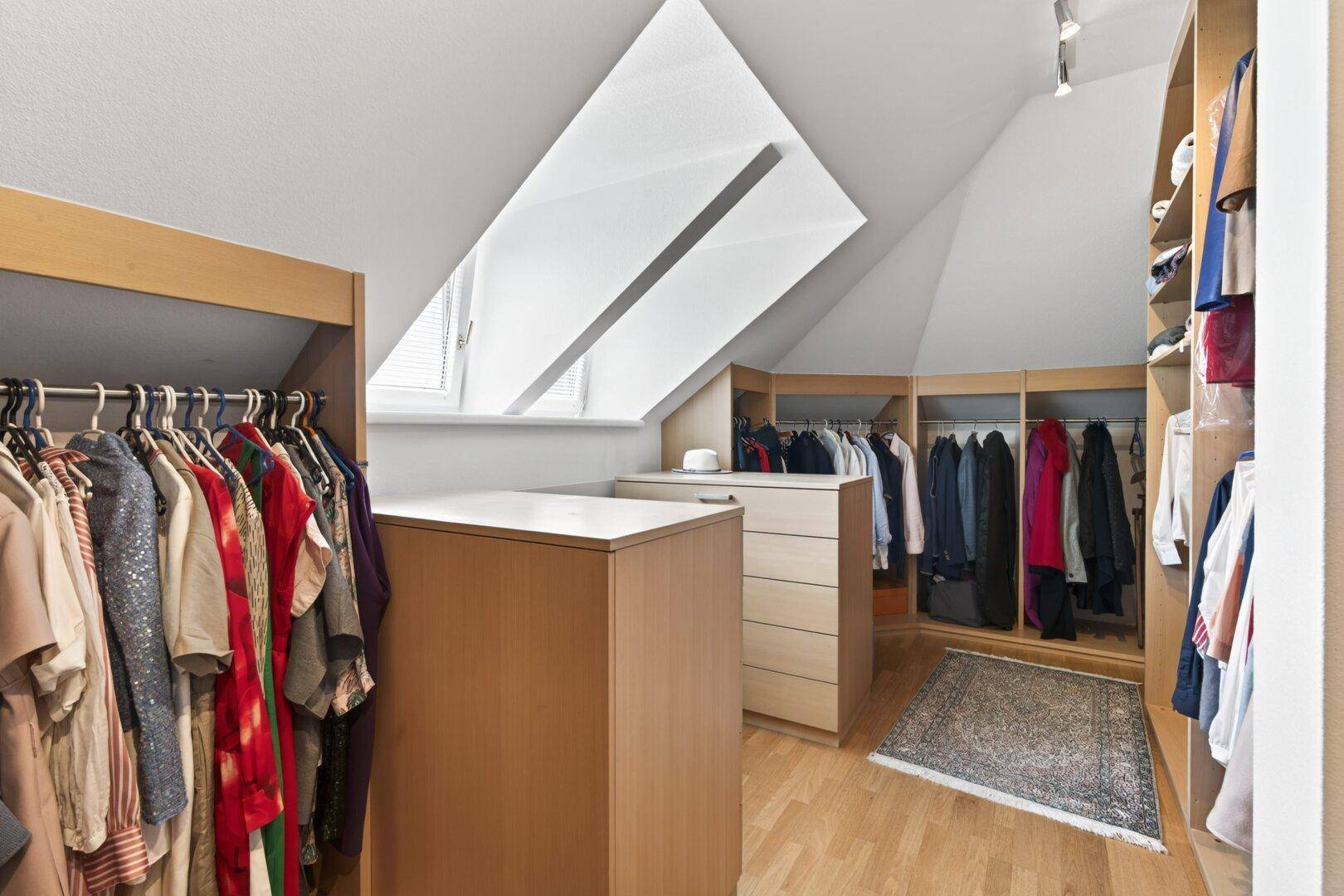 Geräumiger begehbarer Kleiderschrank im Dachgeschoss mit viel Stauraum und Dachfenster.