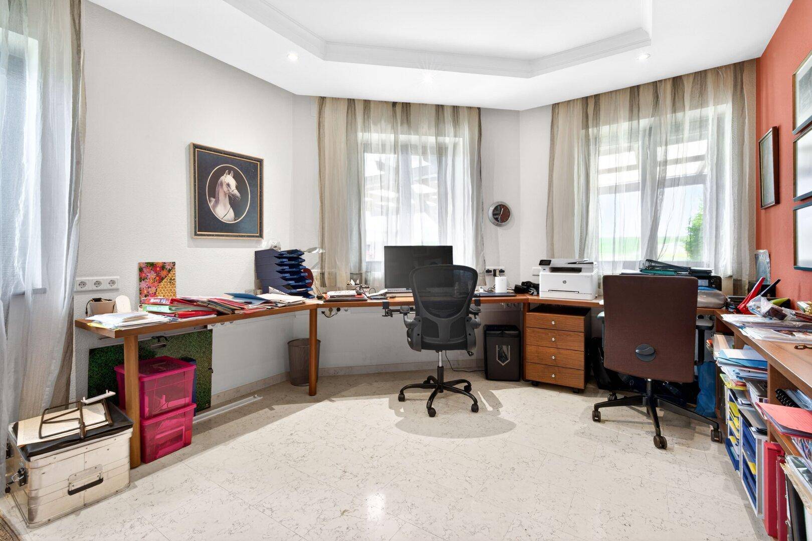Geräumiges Arbeitszimmer mit mehreren Schreibtischen, viel Tageslicht und Blick ins Grüne.