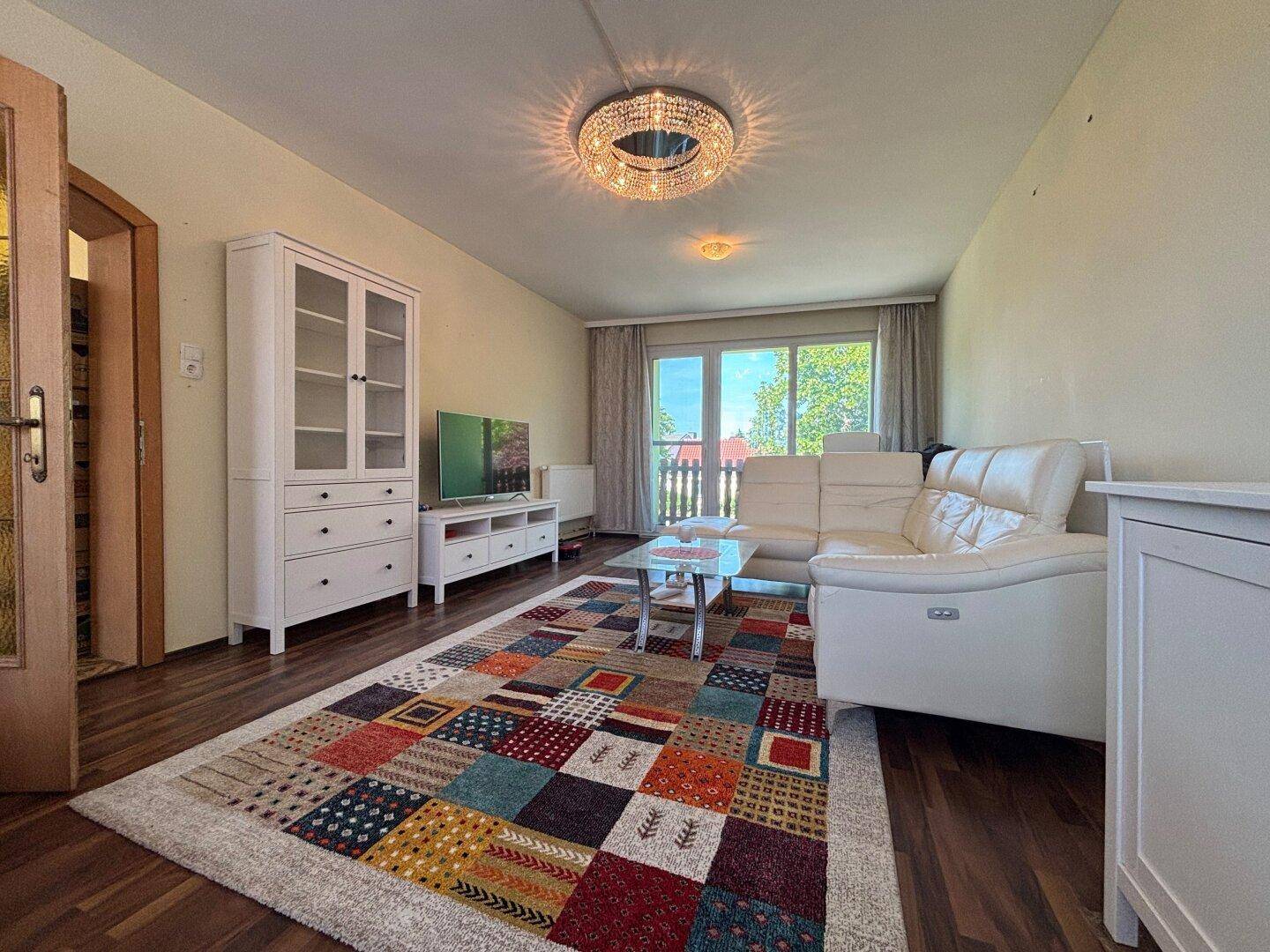 Gemütliches Wohnzimmer mit Sofa, Fernsehmöbeln und Zugang zu einem Balkon oder Terrasse.