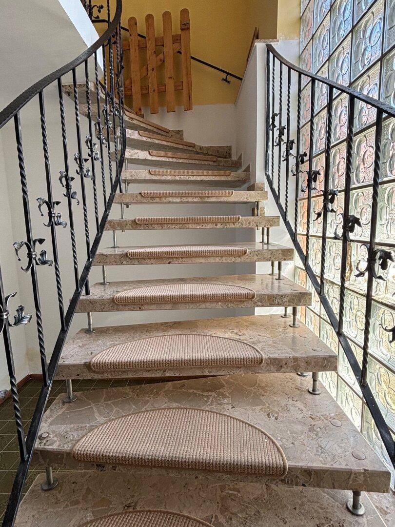 Elegante Marmortreppe mit schmiedeeisernem Geländer und dekorativer Glasbausteinwand.