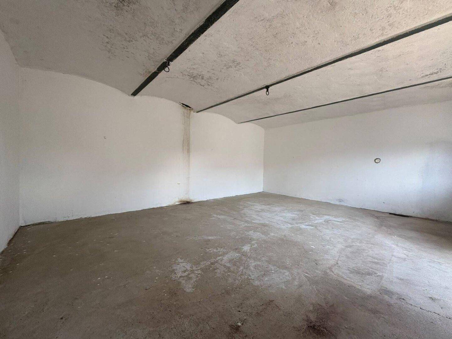 Leerer Kellerraum mit Betonboden und gewölbter Decke, ideal als Lagerfläche.